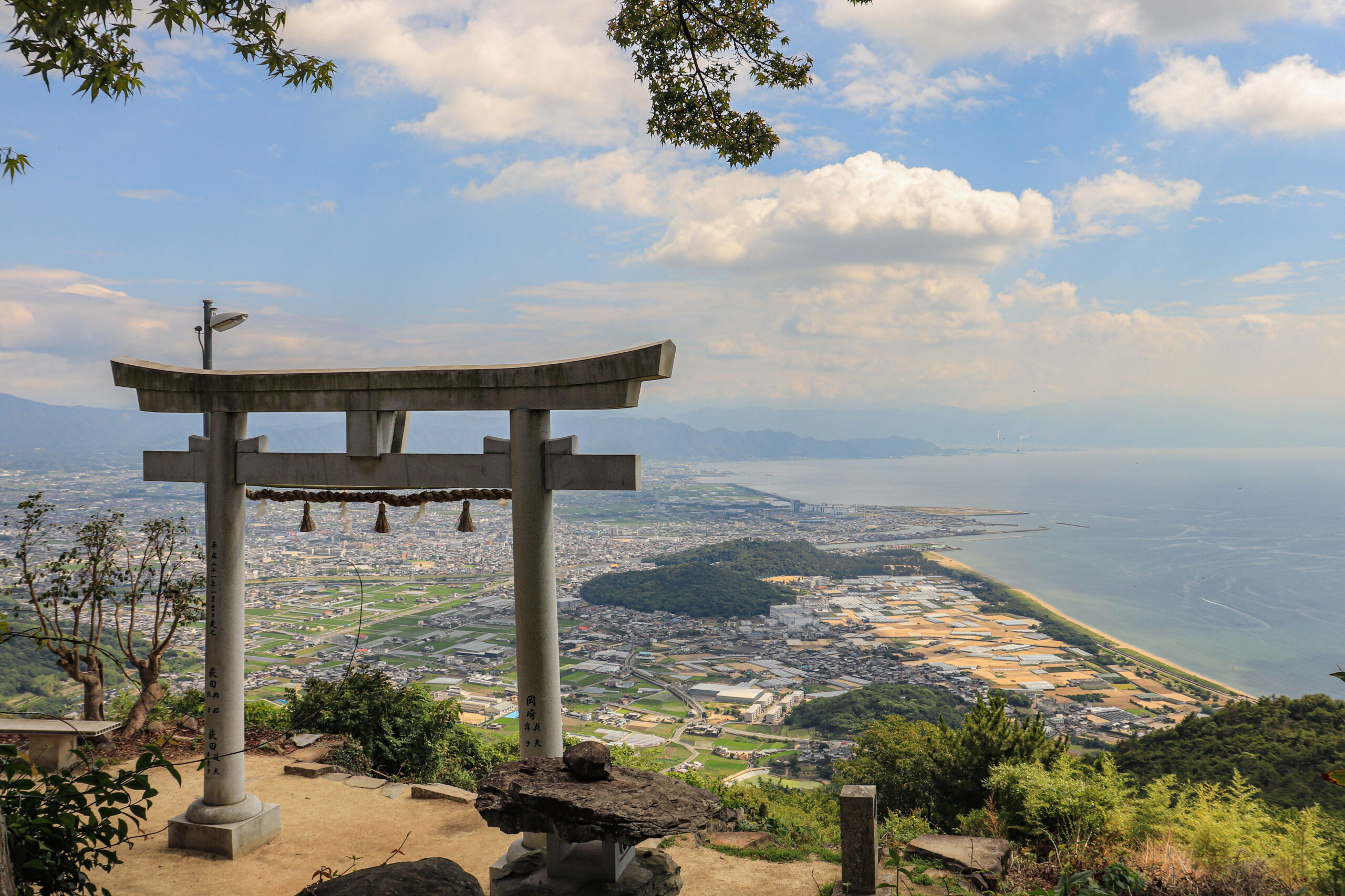 高屋神社の石の鳥居と、その先に広がる観音寺の市街地と瀬戸内海