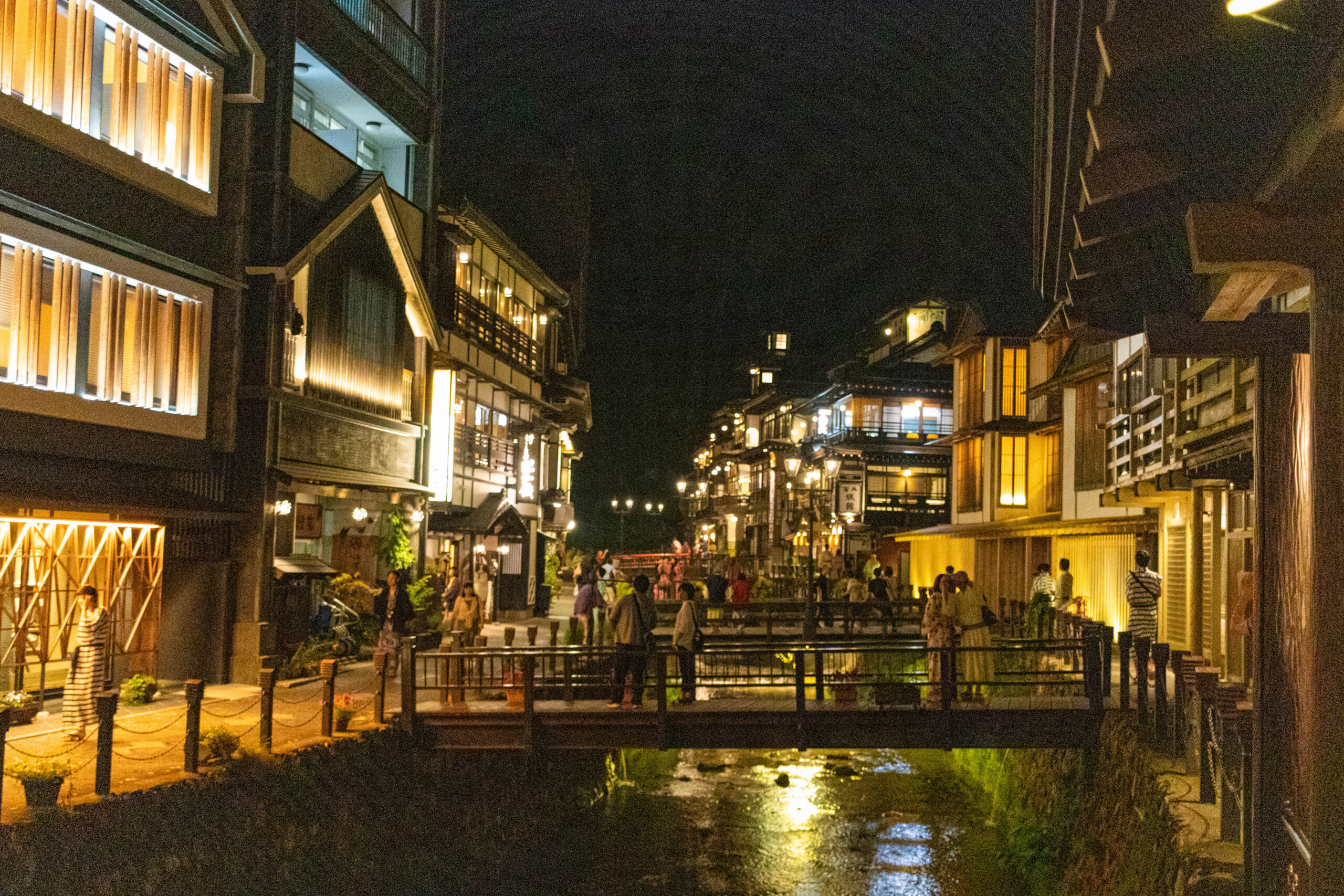 夜の銀山温泉で川沿いの木造旅館に暖色の灯りがともる風景