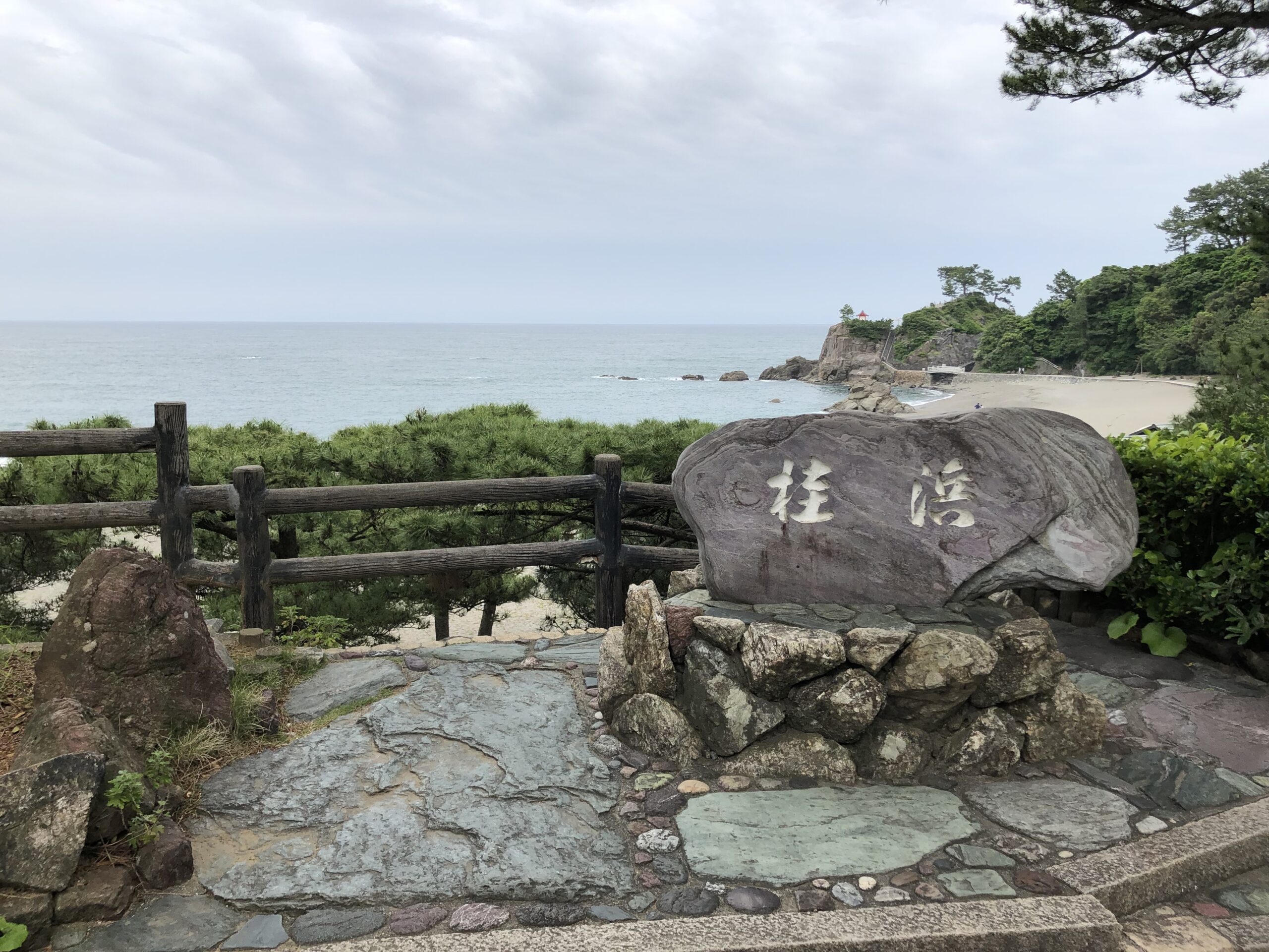 桂浜の石碑と、松林に沿って弧を描く浜辺