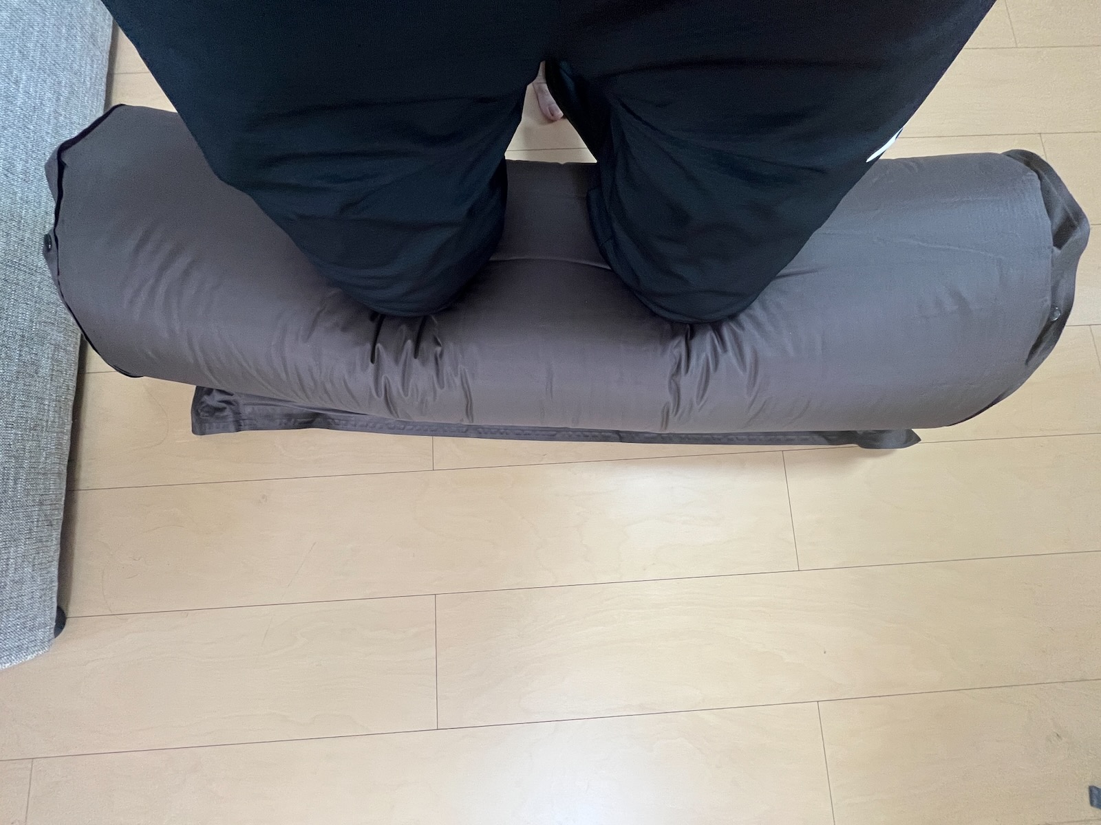 幅のあるマットを丸めながら両膝で押さえている様子