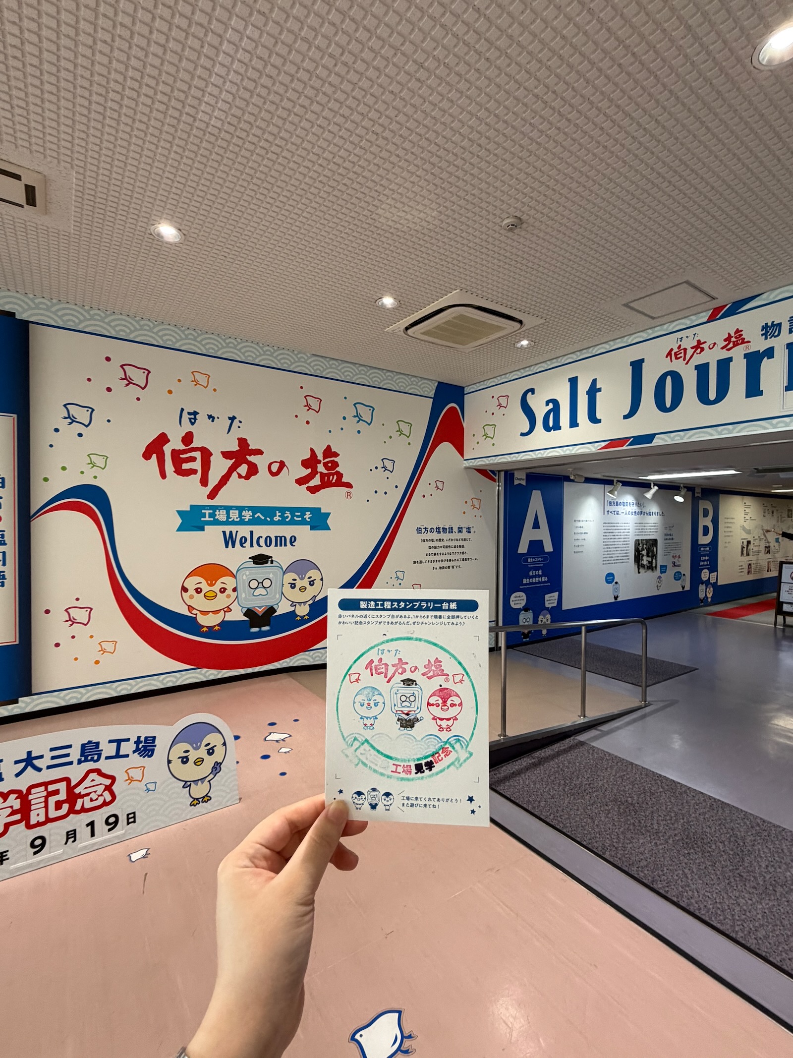 伯方の塩・大三島工場の見学入口と手に持ったスタンプラリー台紙